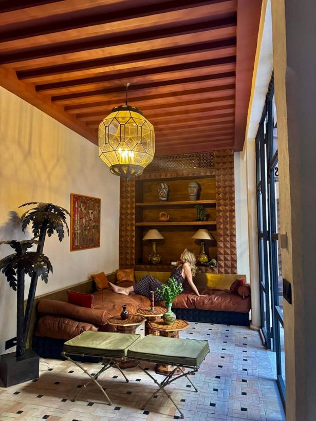 Une invitée se détend sur la banquette du salon, sous la grande lanterne.